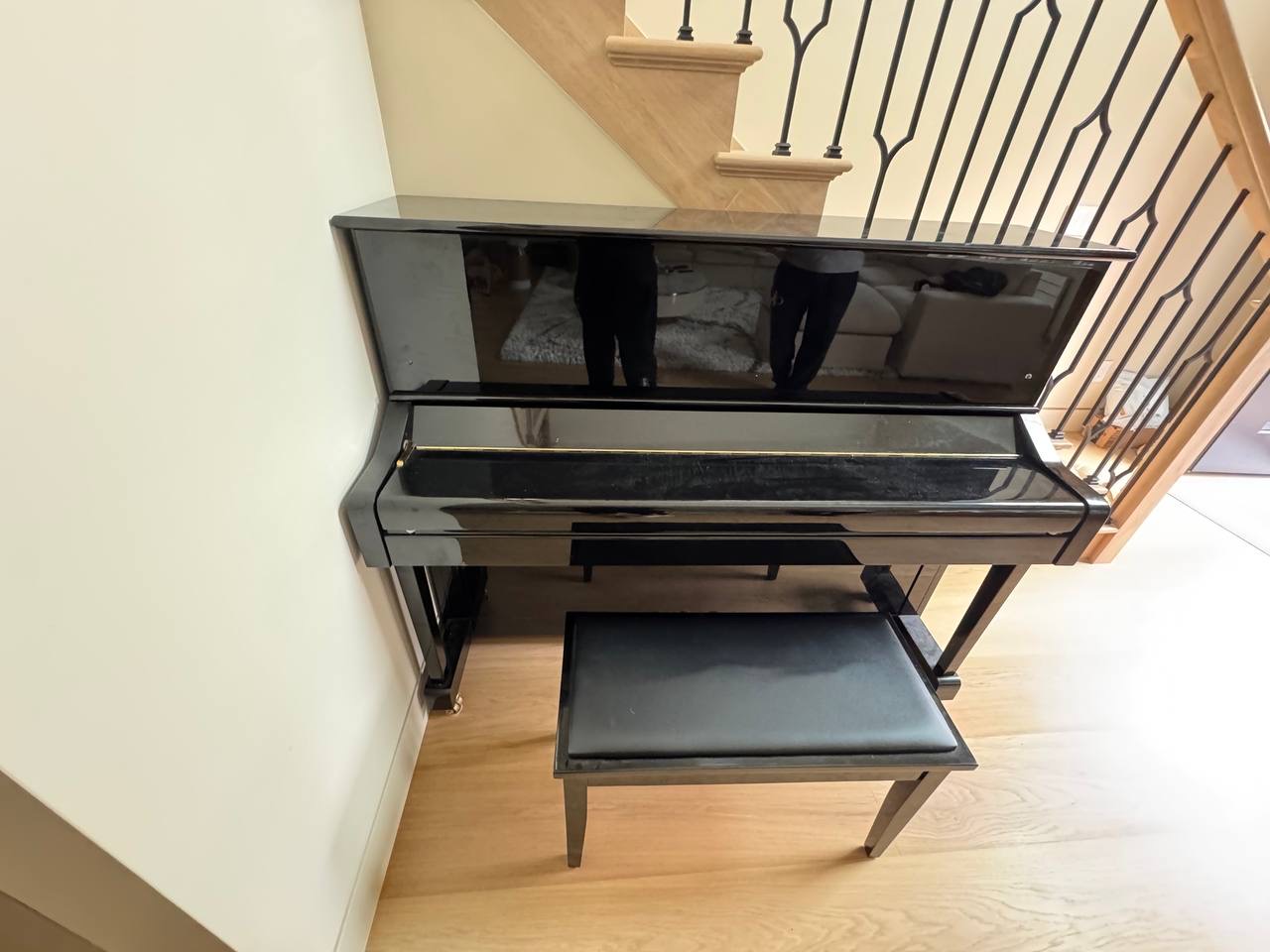 Black upright piano and bench beside a staircase