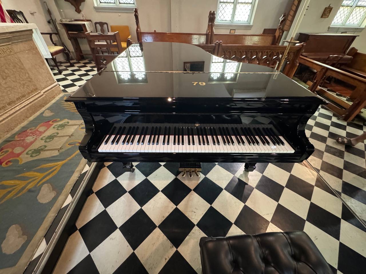 Black grand piano inside a church with a checkered floor