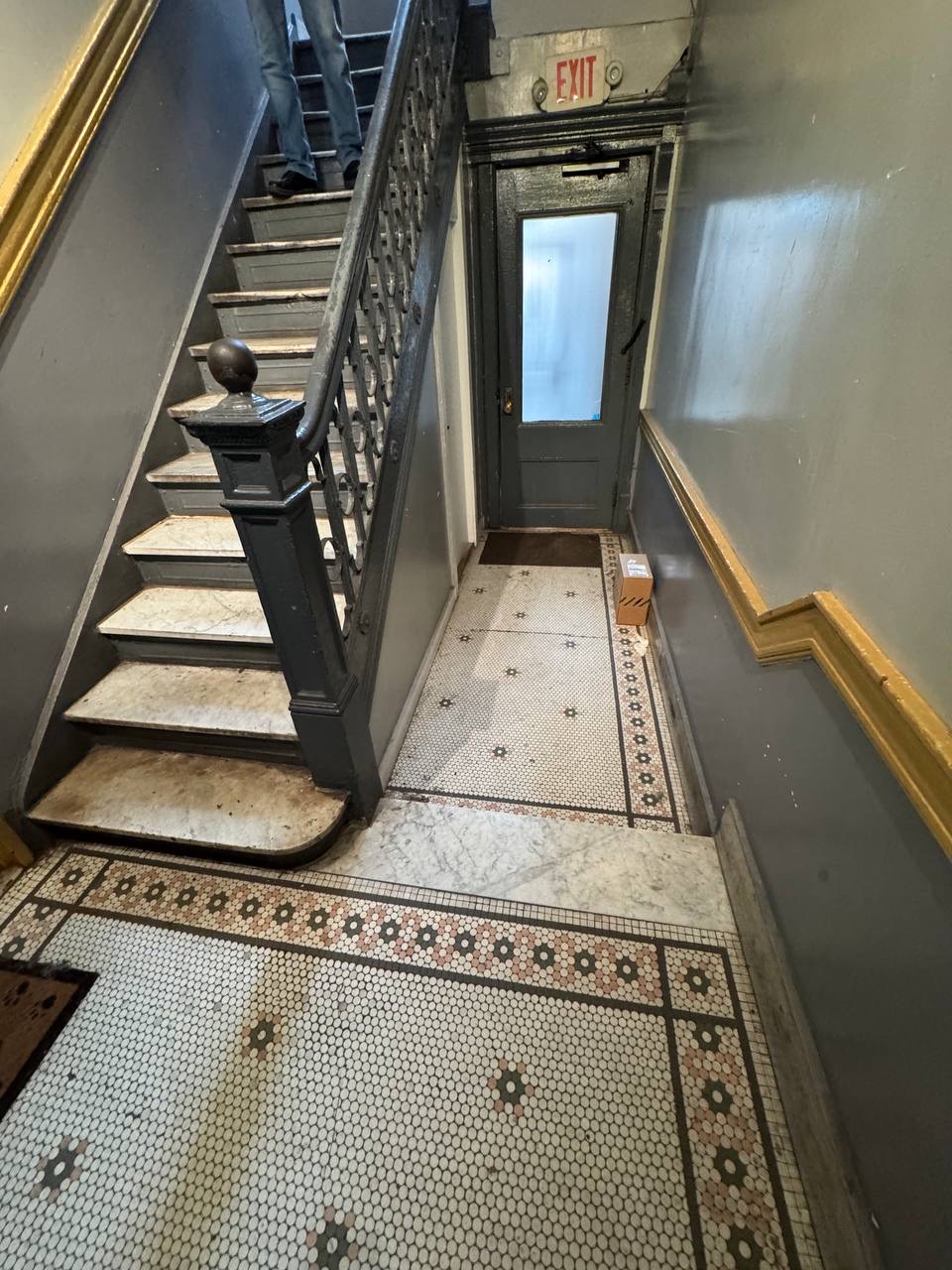 Narrow stairwell showing stairs, a landing, and an exit door